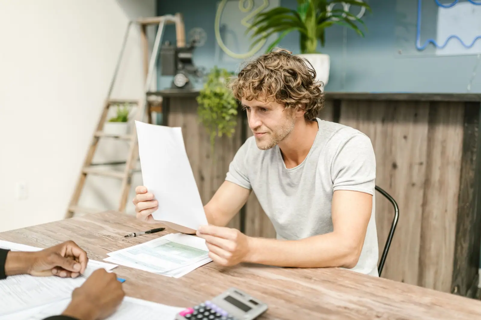A man reviewing paperwork across a wooden table from another person