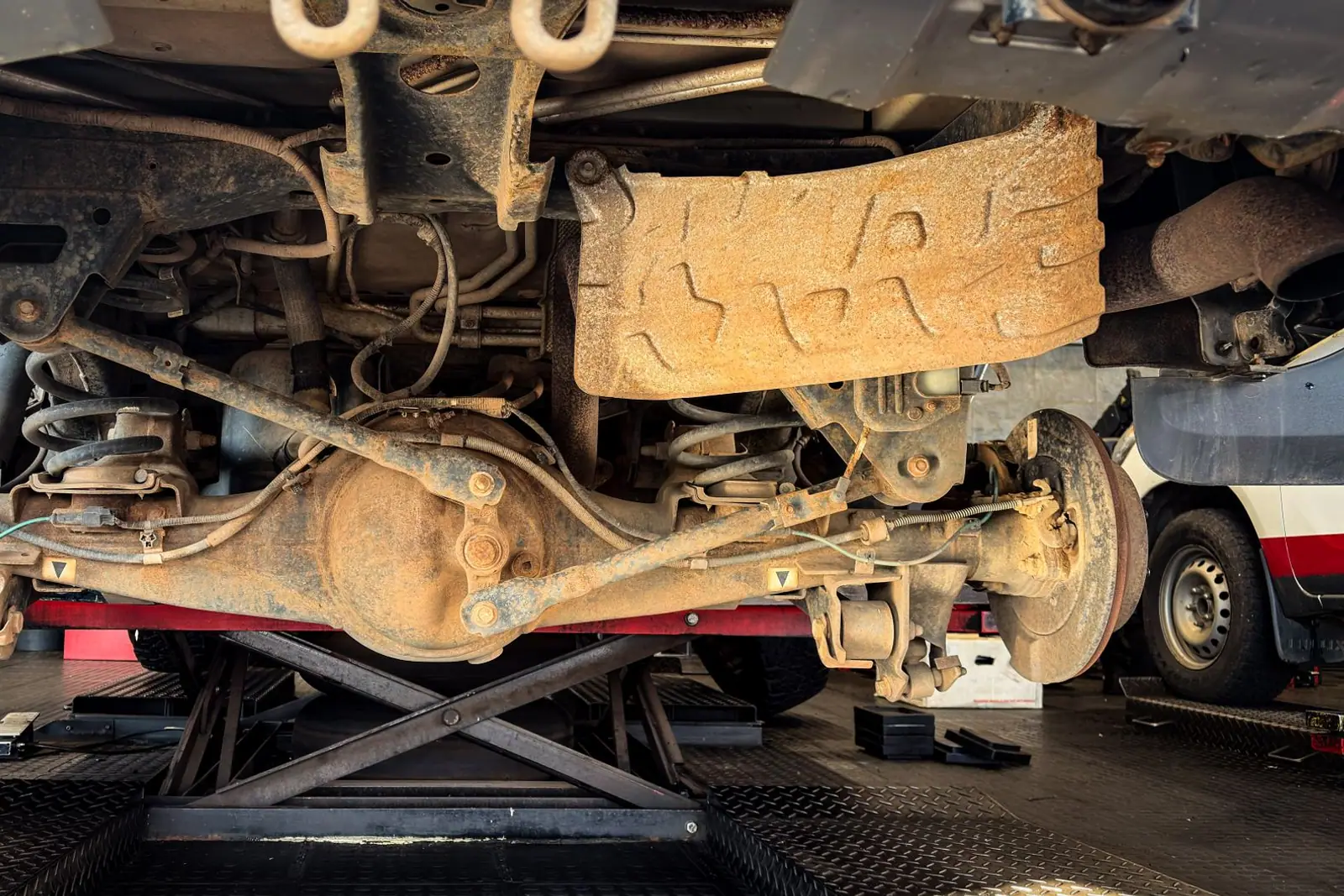 The rusted suspension of a car seen from underneath on a lift